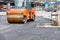 The new road construction site, a heavy orange vibratory roller and a petrol vibratory compactor plate are paired