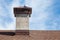 New roof, natural asphalt tile and chimney pipe against blue sky.