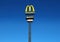 New signboard pole and logos of Mcdonald`s and Mc Drive against blue cloudless sky. It`s one of the first drive restaurant opened