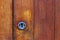 A new silver keyhole on an old wooden front door