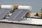 New solar panels for heating water installed on metal roof of local tourist resort next to rocky shore and calm blue sea