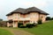 New suburban family house shaped like small light pink castle surrounded with cut grass and grass covered driveway