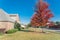 New two story suburban house with power distribution lines and colorful red maple leaves in Texas, USA