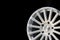 New vehicle rims made from aluminum alloy, multi-spoke silver wheel, close-up on a black background, copy space