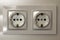 New white shiny plastic electric double sockets on white wall ba