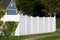 A new white vinyl fence by a grass area with trees behind it green property modern