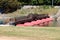 New wooden floating pontoon bridge with strong red floats and center arch secured with wooden fence on calm river