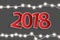 New Year 2018 concept with red paper cuted white numbers on realistic Christmas lights decorations on grey background