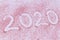 New year 2020 date written on pink sand laying on white background