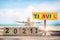New year 2021 to 2022 and commercial plane with rainbow travel word on wooden sign on tropical beach background