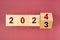 New year 2023 change to 2024. Flip over wooden cube block on red background