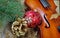 New Year background. New Year`s ball, violin, branches of the Christmas tree and golden fir cones on a wooden table.