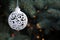 New Year background. A white lace Christmas tree toy in the shape of a ball hangs on a bluish spruce branch