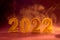 New Year banner with golden sparkling number 2022 in smoke against violet background.