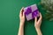 New Year celebration concept. First person top view photo of woman`s hands holding lilac giftbox with violet ribbon bow and