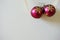 New Year Christmas background. Two burgundy baubles with golden snowflakes on light surface. Holiday decorating concept.