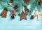 New Year or Christmas background: wooden angels, stars, small fir-trees, cones and branches over blue painted backdrop