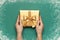 New Year Christmas presents, golden gift in male hands on green background with snow frame top view copy space. Flat lay