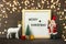 New Year composition of white deer, Santa Claus, lights, skier, tree, gift box, felt board with text Merry Christmas on dark woode