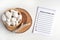 New Year empty resolutions list with a bowl of white pebble anf boho rustic decorations on a white tabe. Mockup with copy space