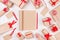New Year festive mock up - blank kraft paper sketchbook surrounded gifts with red bows, pencil on white wooden background.