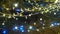 New Year glowing golden and blue garlands hang over Christmas tree. Outdoor winter decoration. Festive city design
