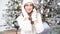 New year portrait of a woman smiling in a white sweater on the background of a Christmas tree