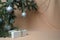 New Year`s decoration. Spruce branches with silver balls, a gift box on a beige wavy background made of chiffon