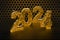 New Year`s Eve hive with bee on honey comb  Shiny hexagonal gold number 2024 on a black background with bee