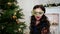 New Year\'s party girl in the masquerade mask, celebrate Christmas near the Christmas tree, mysteriously looking at the