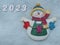 New Year\\\'s snowman on the background of white snow and the numbers of the new year 2023.