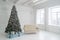 New Year studio interior. Christmas tree is decorated with balloons, with Christmas gifts under it. White sofa stands