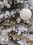 New Years toys on the snow-covered branches of a Christmas tree. Glass sphere, beads. Festive background. New Year`s and Christmas
