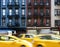 New York City street scene with yellow taxis driving past a block of old apartment buildings in the Upper East Side of Manhattan