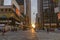 New York City, USA - June 7, 2017: Manhattanhenge in New York. Sun setting between buildings. People crossing street in zebra