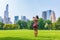 New York City woman tourist taking photo with phone of NYC Skyline in Sheep Meadow Central Park. Summer travel vacation