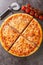 New York style pizza is a large, thin crusted pizza with cheese and tomato sauce closeup on the board. Vertical top view