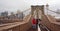 NEW YORK, USA - 12 JULY 2019: Pedestrians walk over the Brooklyn Bridge in cloudy day