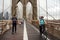 NEW YORK, USA - 12 JULY 2019: Pedestrians walk over the Brooklyn Bridge at sunset