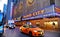 New York USA, urban classic building, colors and neon lights of Radio City Music Hall in Manhattan with urban traffic and yellow t