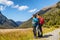 New Zealand hikers backpackers tramping on Routeburn Track, famous trail in the South Island of New Zealand. Couple looking at