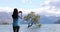 New Zealand tourist taking phone pictures of Wanaka Lone Tree at lake