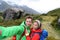 New Zealand travel selfie happy couple backpackers hiking. Travel selfie couple hikers taking smartphone picture on