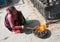 Newari woman kindles the sacrificial fire in hindu temple in Bhaktapur, Nepal