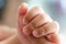 Newborn Asian baby left hand holding finger of her mother