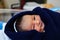 A newborn asian baby wrapped in navy blue towel looking at the camera and smiling with dimple in cheeks