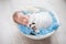 Newborn baby boy in a cocoon in a white bowl on a blue rug