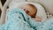 Newborn baby boy laying in his cradle and playing with soft blue blanket.