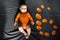 Newborn baby boy six months lying next to pumpkins