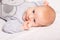 Newborn baby boy smiles lies on white background indoor closeup. Happy, cute and pretty. Home care and cozy. Motherhood